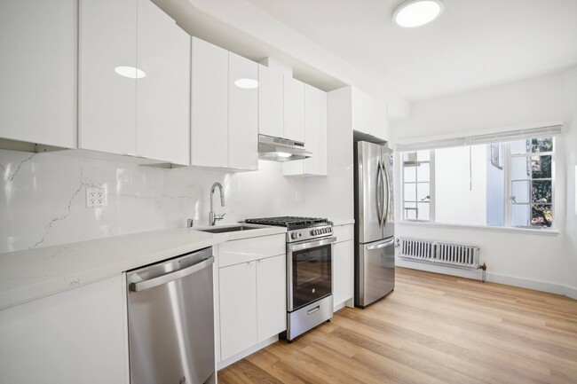 Kitchen with multiple cabinets, refrigerator, stove, range hood, and sink - 2363 Le Conte Avenue