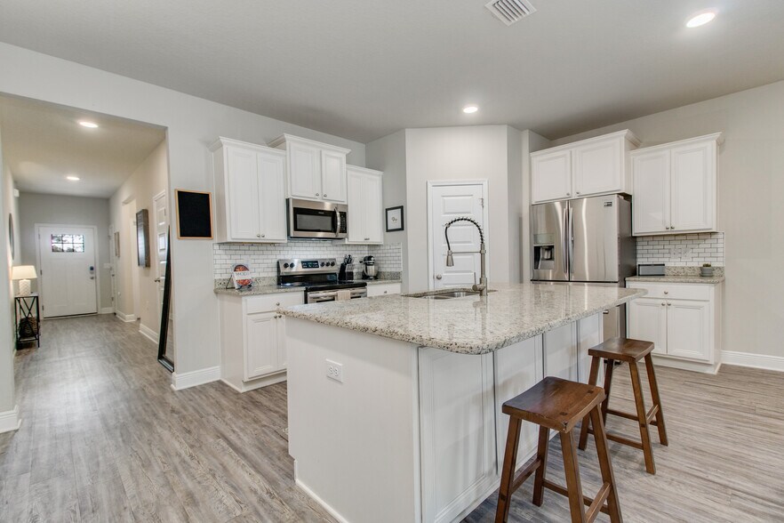 Kitchen with granite countertops, spacious breakfast bar for hosting, and walk in pantry. - 3618 Hawks Landing Cir
