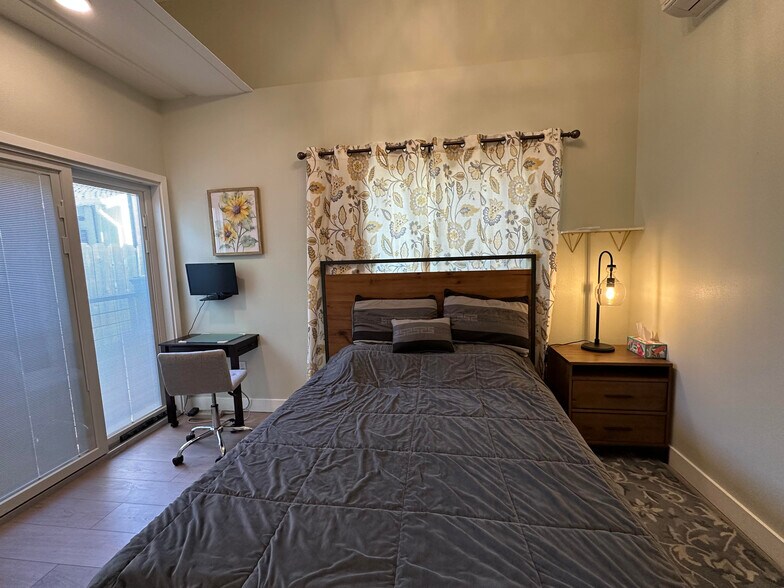 Bedroom 1 with small desk and wall-mounted computer monitor - 1490 Ash St