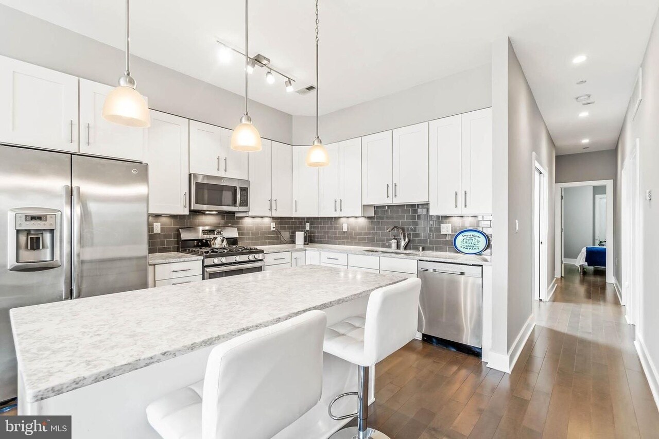 Open kitchen featuring gas range, stainless steel appliances, built-in microwave, marble countertops - 3821 14th St NW