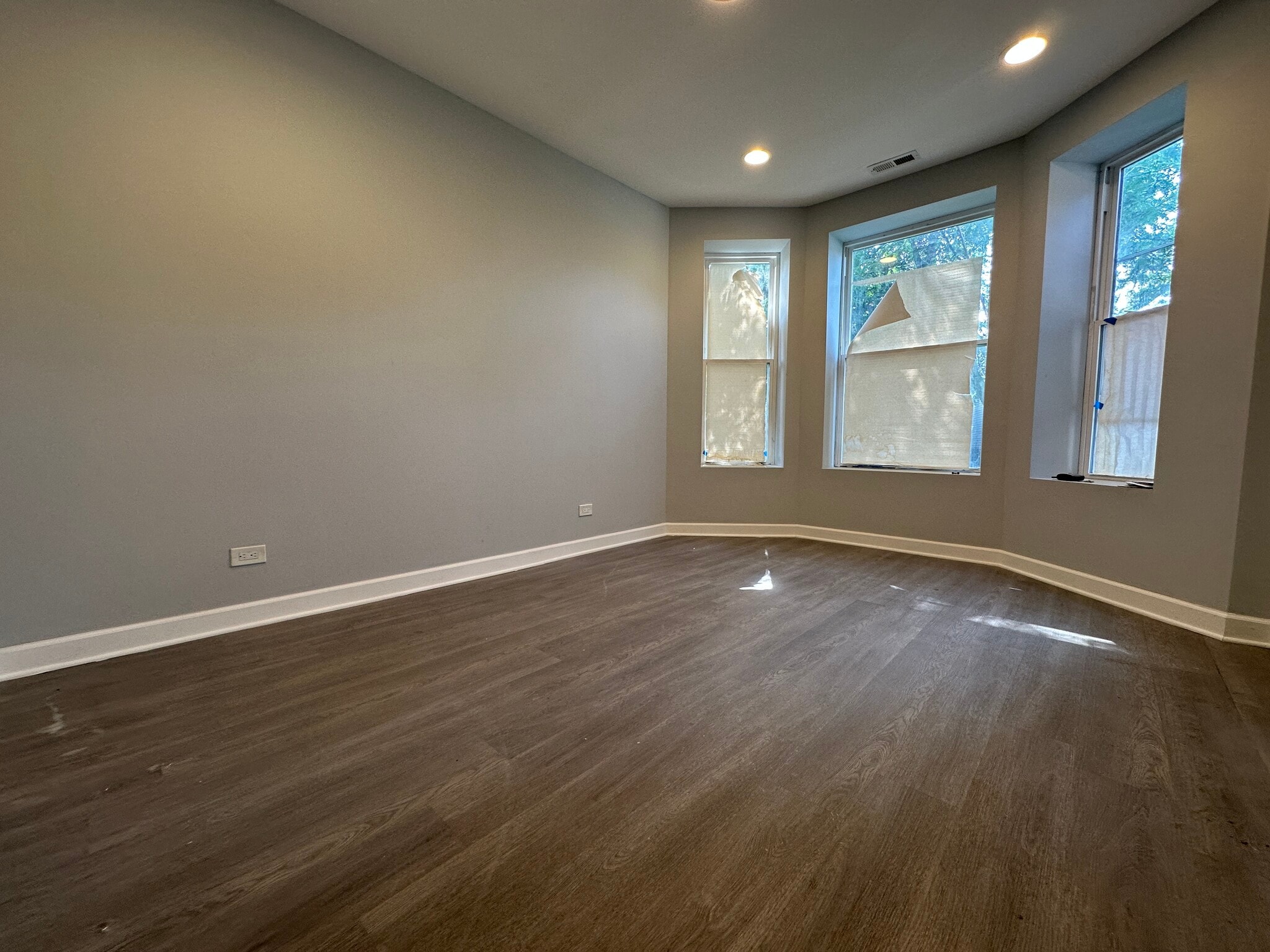 BrightLarge living room with plenty of natural light from three bay windows and brand-new flooring - 5653 S May St