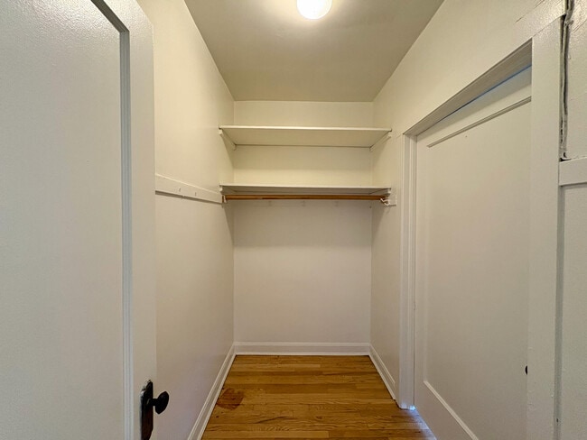 Spacious walk-in closet with built-in wooden shelving and elegant hardwood flooring. - Ivanhoe