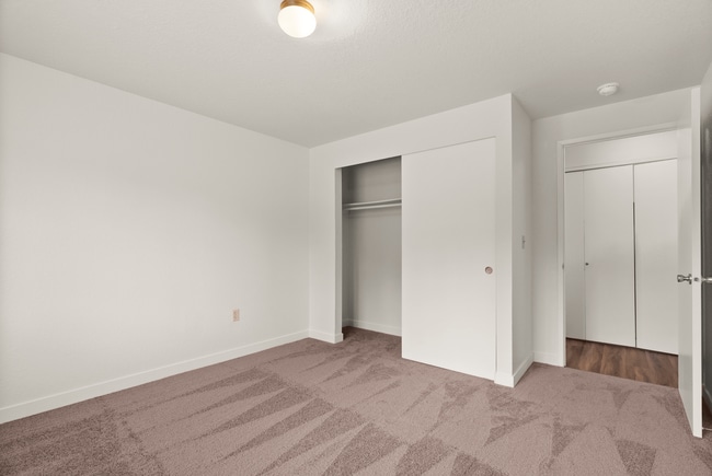 Bright and inviting bedroom with plush carpet, built-in closet, and modern lighting. - Windemere Apartments