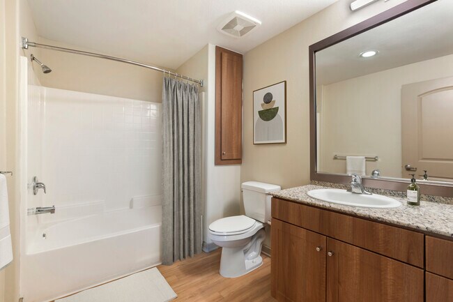 Updated Finishes bath with oak cabinetry, beige speckled granite countertops, and hard surface flooring - Avalon San Dimas