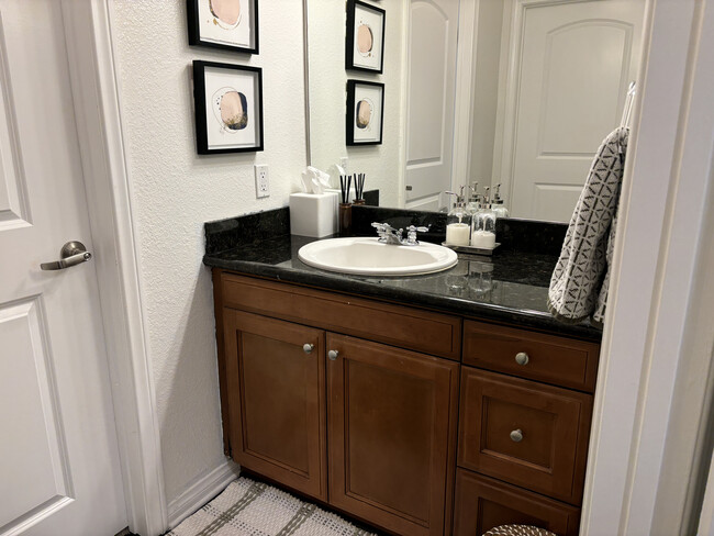 Elegant bathroom vanity with black granite countertops, ample storage, and modern lighting - 3740 Santa Rosalia Dr