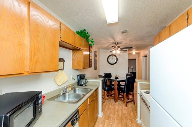 Kitchen with Hardwood-Style Flooring, Wood Cabinetry, and White Kitchen Appliances - City Pines Apartment Homes