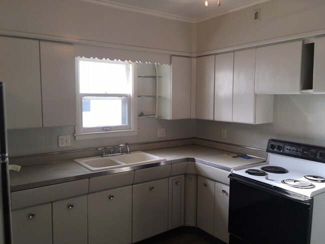 A view in the kitchen of the cabinets, sink, and stove. - 1729 7th Ave S