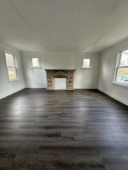 Unfurnished living room with dark hardwood / wood-style flooring, and a textured ceiling - 1247 N Florissant Rd