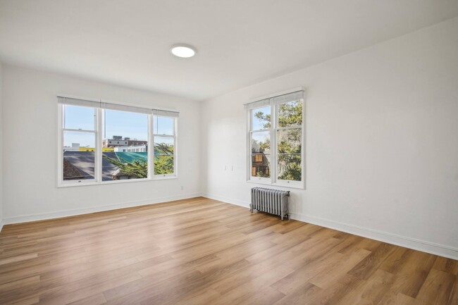 Living area with two large windows and wood-like flooring - 2605 Haste Street