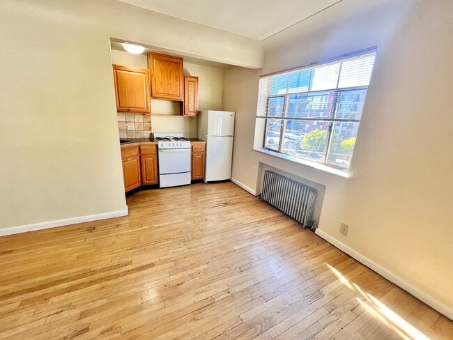 Step into this bright kitchen space featuring stylish wooden cabinetry and natural light. - Hillside Apartments