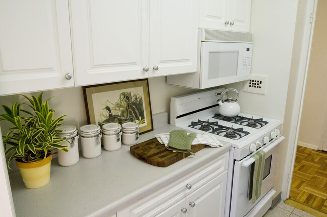 Kitchen with white countertop, white cabinetry, white appliances and hard surface flooring - eaves Glover Park