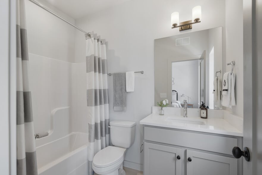 Stylish and functional full bath with tub/shower combo and quartz vanity. - 358 E Village Ln