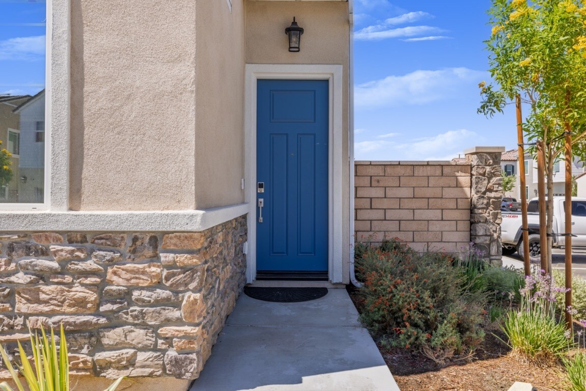 Welcoming front entrance featuring a stylish blue door, stone-accented exterior, and landscaped walk - 26549 Brightstone Dr