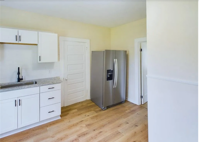 Kitchen: A fresh, updated kitchen with white cabinets, sleek black hardware, and granite countertops - 1011 Elm St