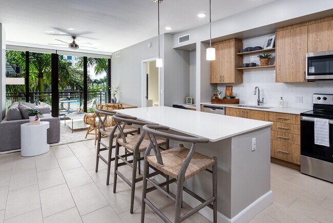 Open concept kitchen with quartz countertop, island, stainless steel appliances and tile backsplash - Avalon Doral
