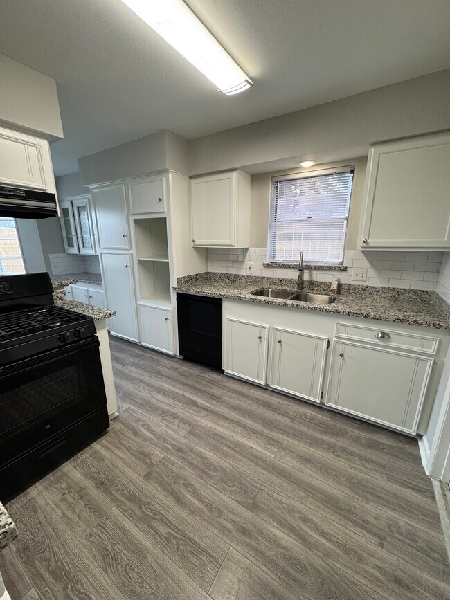 Functional kitchen with granite counters, white cabinets, and black appliances. - 11927 Troulon Dr