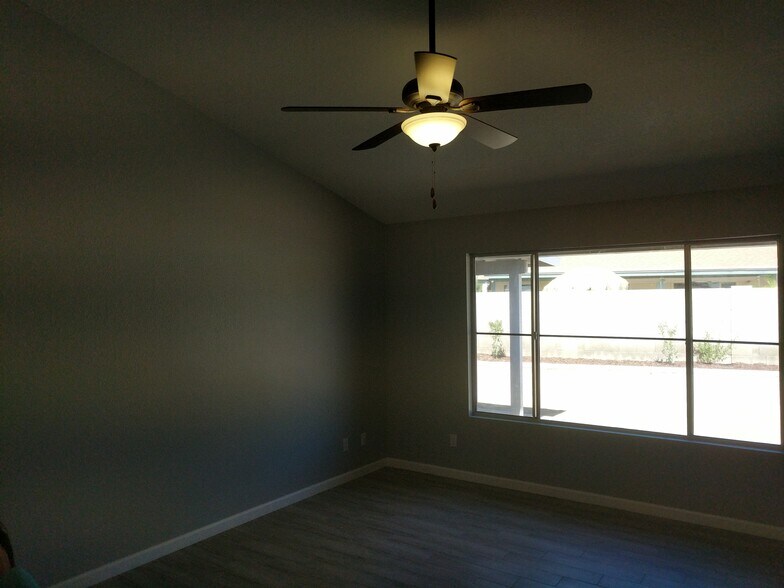 Living Room / front room ceiling fan and large window open to backyard. North and East walls - 14101 N 78th Dr