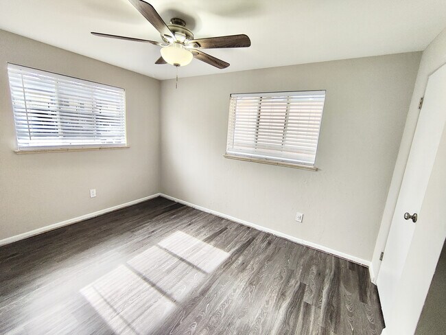 Bright and airy room with elegant dark wood flooring and modern ceiling fan, perfect for a cozy bedroom setup. - 8867 W 54th