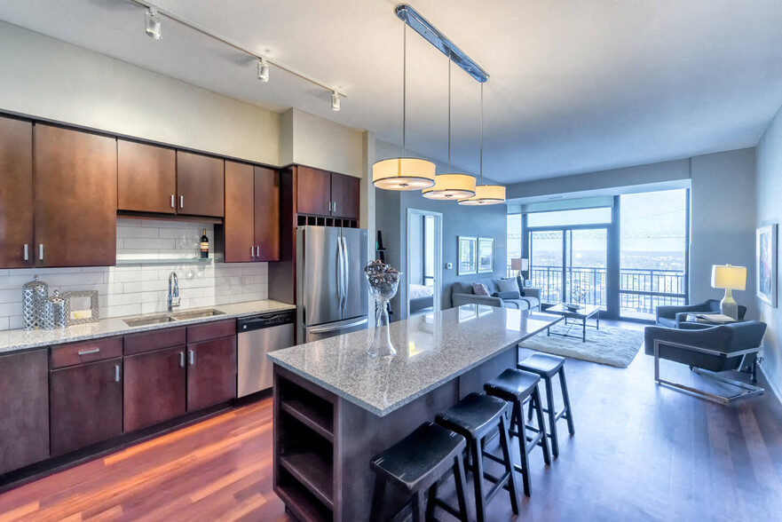 Nic on 5th Apartments in Minneapolis, Minnesota- Large common room with wooden cabinets, floors and granite countertops - NIC on 5th