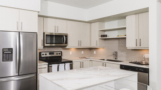 Stunning kitchens with french door stainless steel refrigerators, quartz counters, tile backsplash, and built in shelving - Modera Edgewater