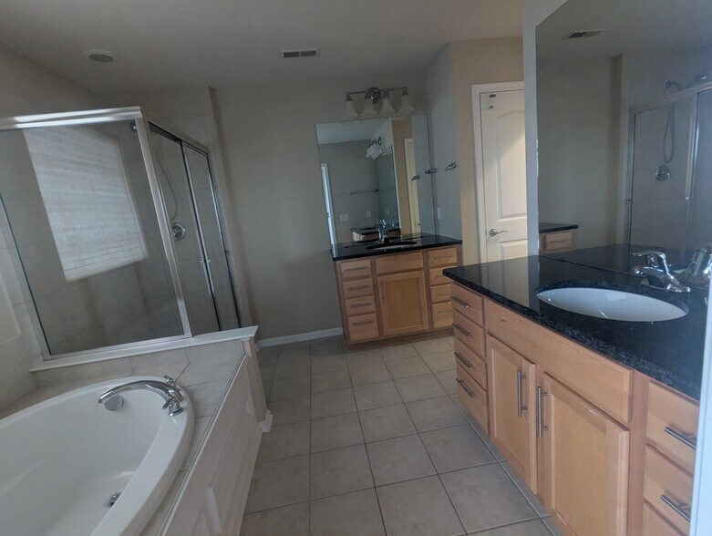 Primary suite bathroom with two vanities, a soaking bathtub and a large tiled shower - 6465 Park Pointe Ct