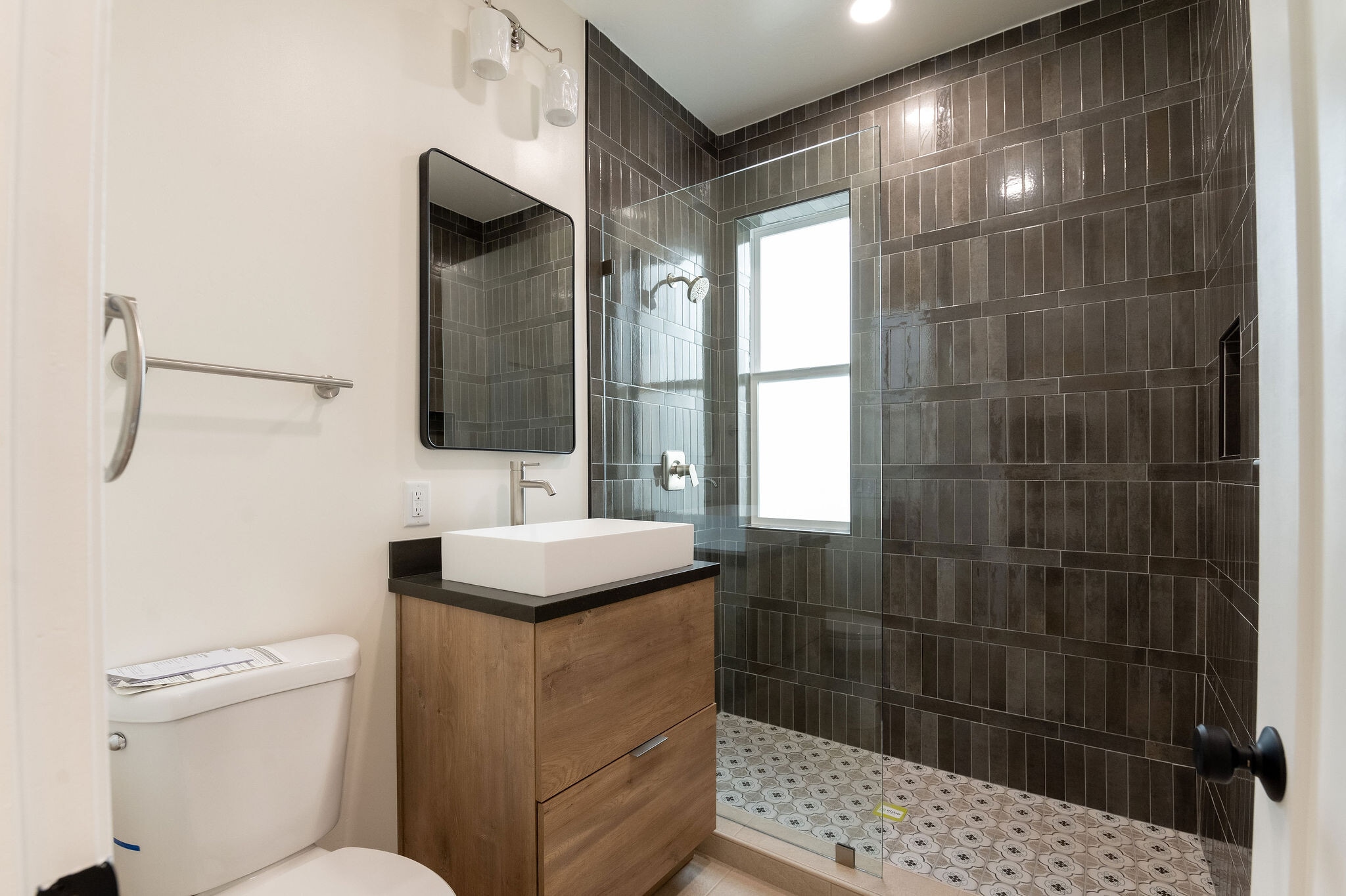 Hall bathroom. Floor to ceiling porcelain brown tile. European vanity with quartz counterop. - 4774 Bancroft St