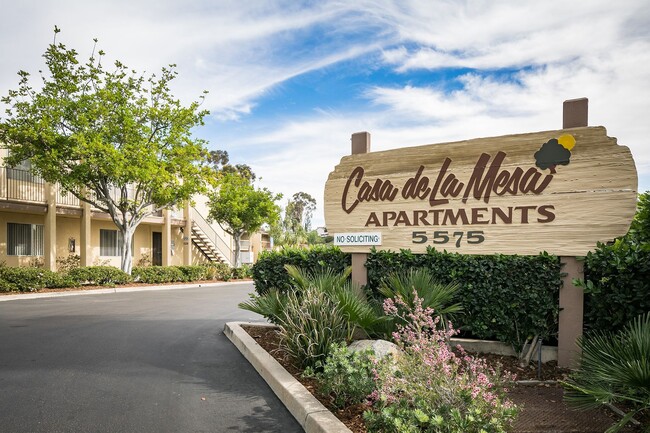 Image of the front entrance monument sign sitting on a bed of flowers. - Casa De La Mesa