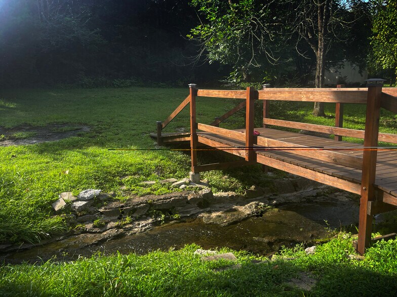Wooded backyard with bridge crossing serene stream. - 1404 Winthorne Drive