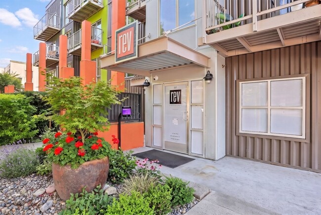 Secure building entrance at REV Fremont in Seattle, highlighted by colorful architectural accents and front landscaping. - REV Fremont
