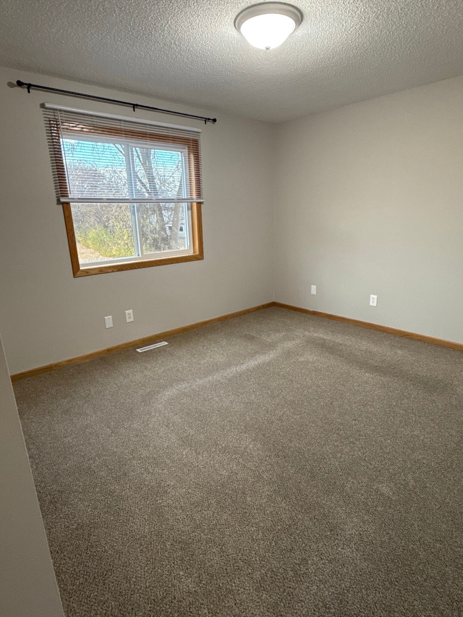 Large upper-level bedroom with big window, fresh paint, and neutral carpeting. - 9092 Goldenrod Ln N
