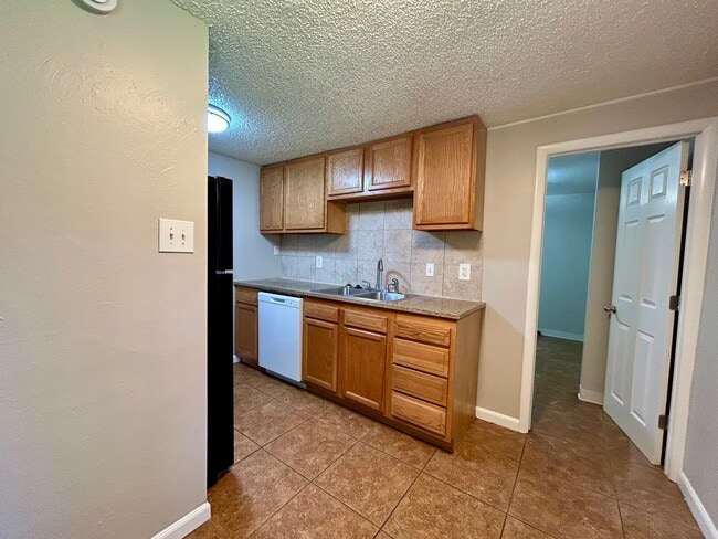 Charming kitchen with warm wood cabinets, modern appliances, and tiled flooring, offering a cozy culinary space. - Boardwalk Apartments