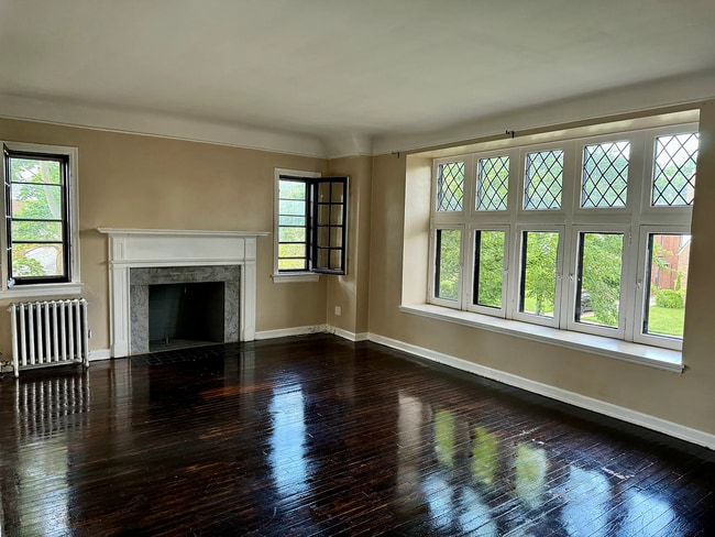 Large living room with hardwood floors, decorative fireplace, and oversized windows. - 3682 Glencairn Road