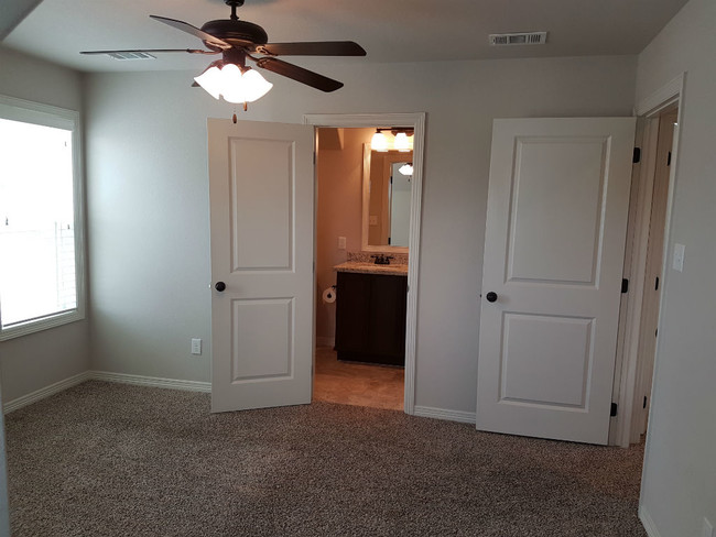 Bedroom with ceiling fan and private bathroom. - 113 Ehlinger Dr