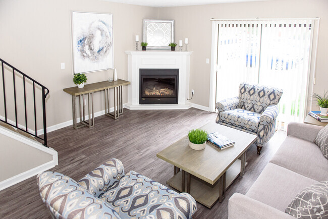 Living area with faux wood flooring, sliding doors to patio, and fireplace (in select uniits) - Chartwell Townhouse Apartments