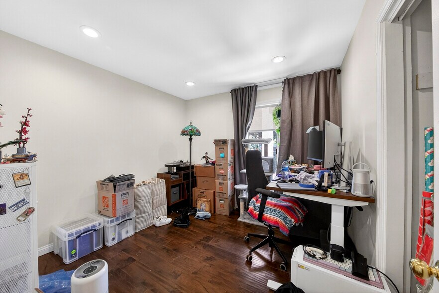 A versatile secondary bedroom with rich hardwood flooring and a front yard-facing window. - 5214 Dawes Ave