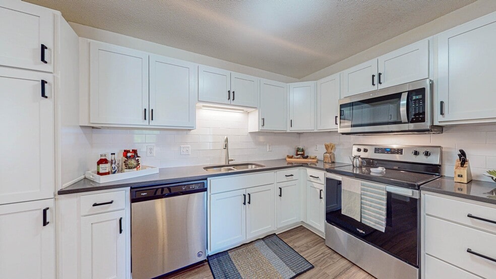 Kitchen with white cabinets and stainless steel appliances - Creekside Apartments