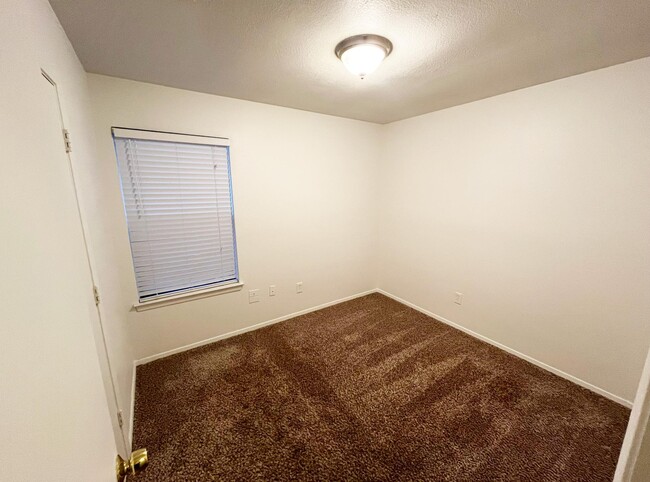 The second bedroom has a single-hung window with white mini blinds matching the fresh white paint - 4917 Jamesway Rd