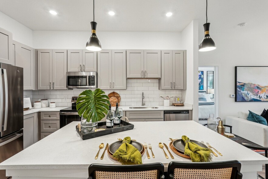 A modern kitchen with a dining table set for two. - Tapestry University Park