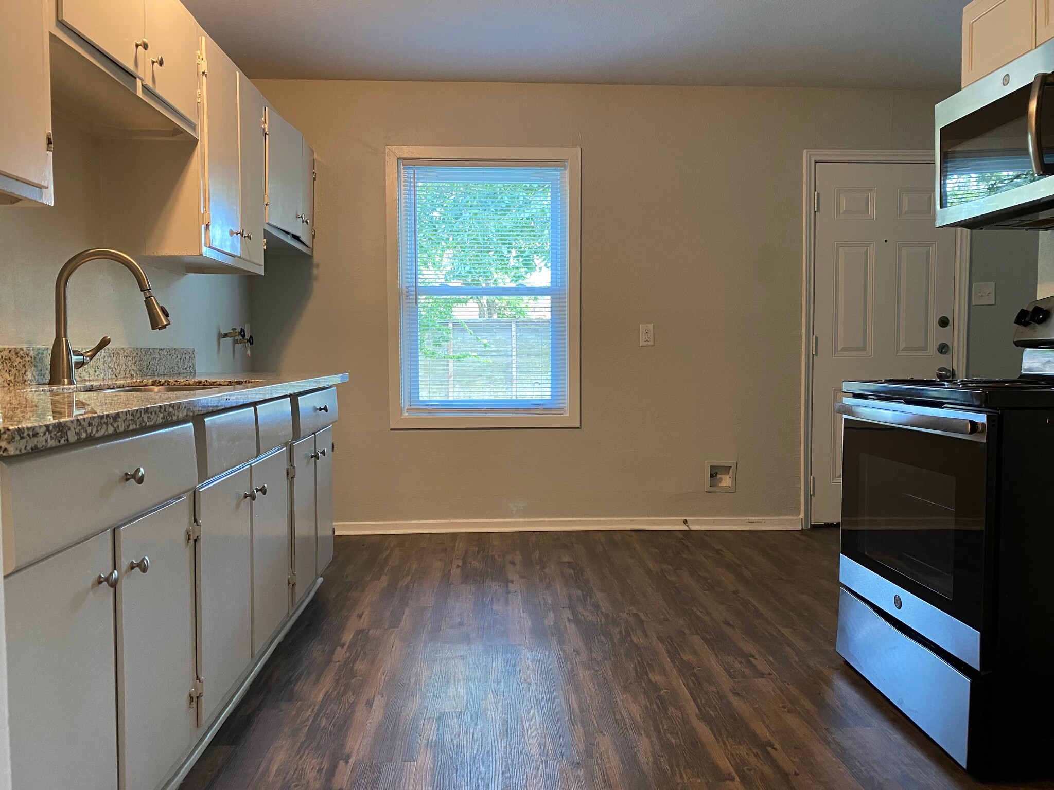 Kitchen with granite countertop, stove/oven, microwave, hooks for washer, fridge (coming next week) - 4230 Friar Point Rd