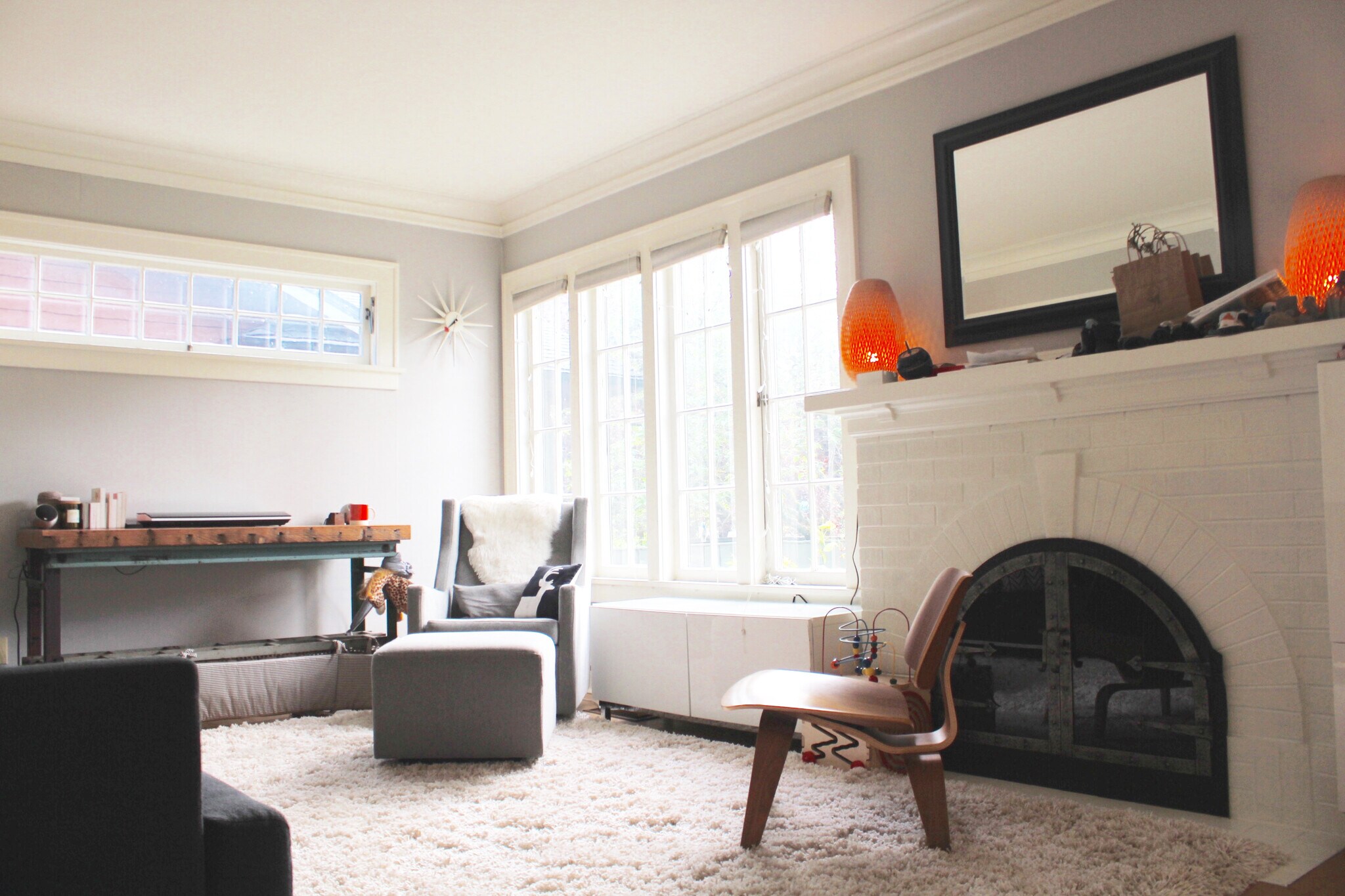 Gorgeous recently serviced fireplace in light filled living room with tall casement windows and translucent cellular window coverings throughout. - 2635 NE 30th Ave