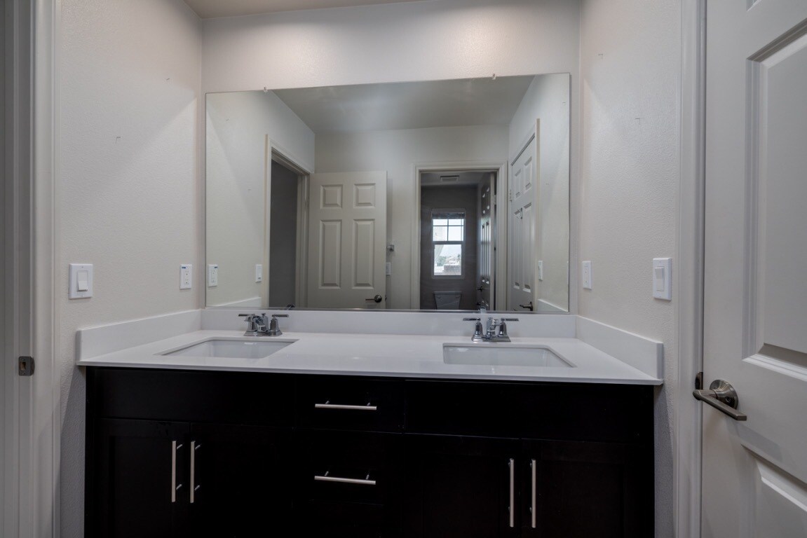 Elegant shared upstairs bathroom featuring dual sinks with dark wood cabinetry - 26549 Brightstone Dr