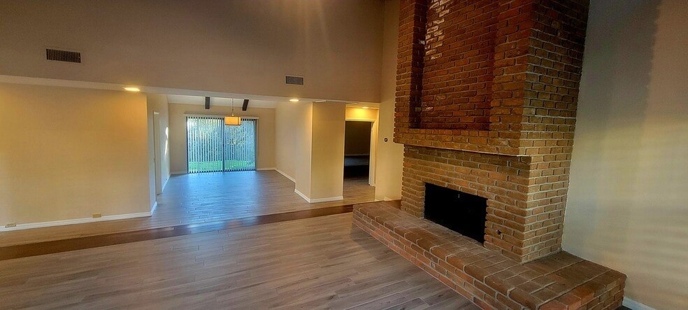 Living room with brick fireplace and dining room - 16139 Ladera Piedra Way