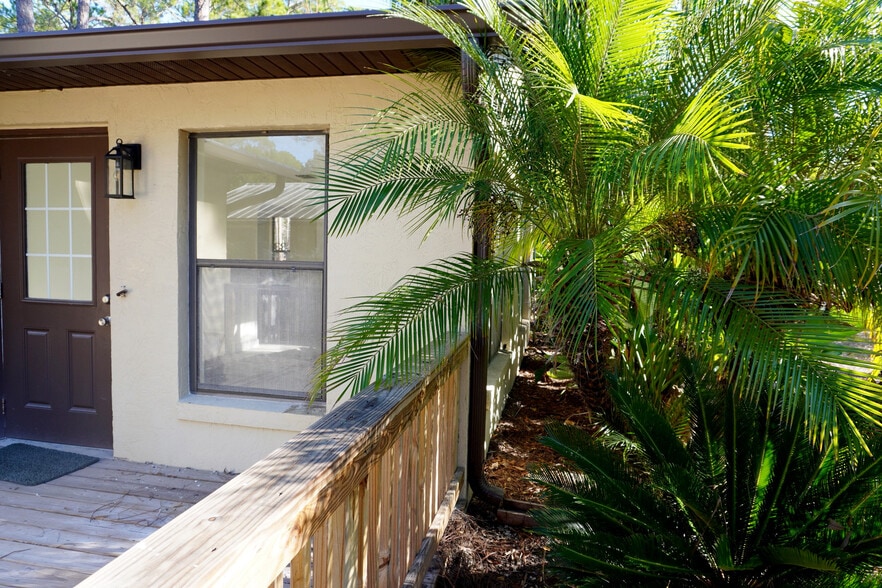 Side entry with window and lush palms—cozy charm of your Yankeetown Nature Coast retreat. - 33 63rd St