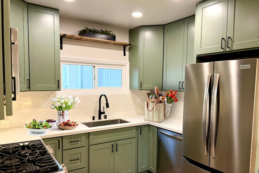 The upgraded kitchen features sage green cabinets, quartz counters and stainless appliances. - 2824 S Orange Dr