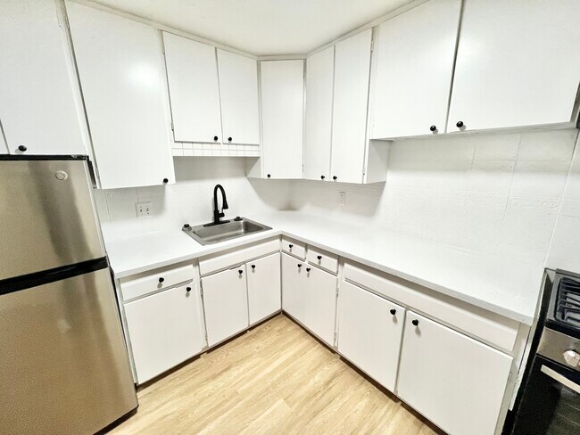 Experience the sleek design of this modern kitchen with ample storage and contemporary finishes. - Melody Apartments