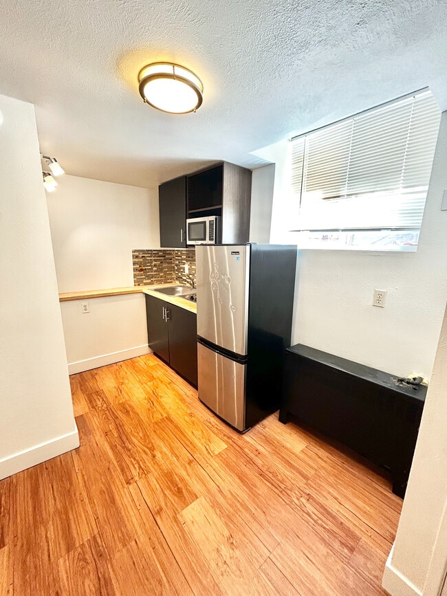 Chic modern kitchen with stylish backsplash, sleek cabinetry, and natural light highlighting the hardwood floors. - Plaza West