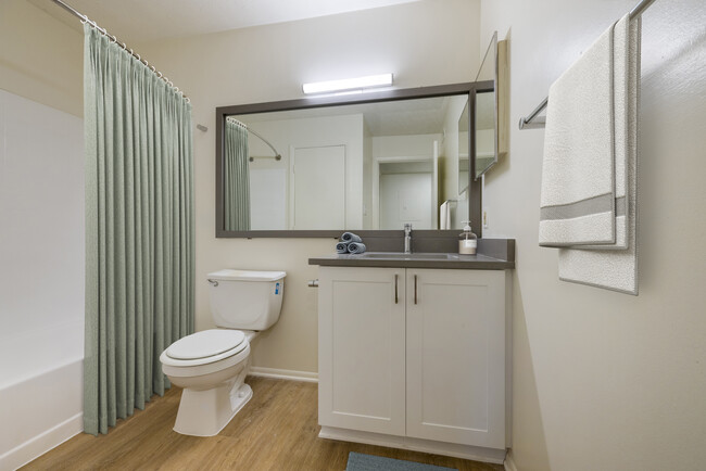 Renovated Meadows II bath with white cabinetry, grey quartz countertops. and hard surface flooring - Avalon Fairway Hills-Meadows