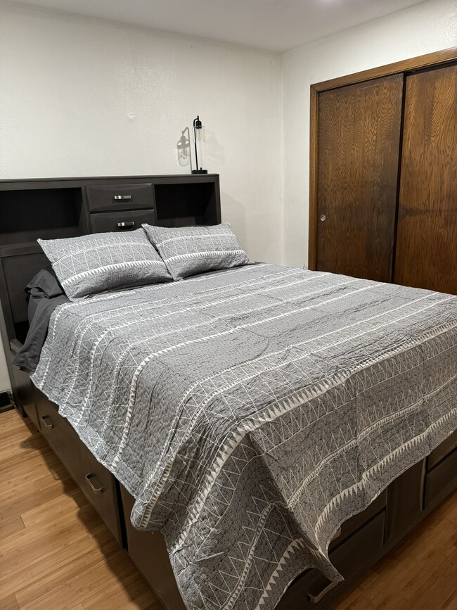 second bedroom with underbed drawer storage, night stand and lamp and closet - 4449 Charles St