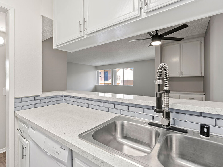 White tiled kitchen with stainless steel farmhouse style sink. - Riverbridge Apartments