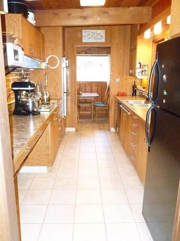 Galley style kitchen with double oven. The new refrigerator is white with matching white dishwasher. - 1705 NE Lower Dr
